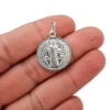Primer plano del dije medalla de San Benito en plata 925 italiana mostrando detalles y acabado brillante y em alto relieve.